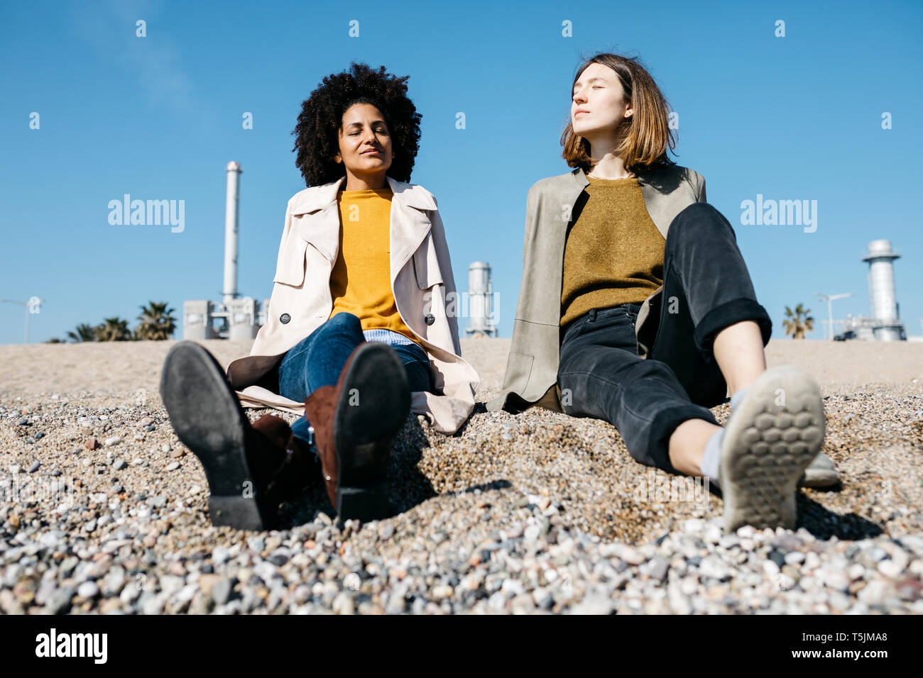 Due amici seduti sulla spiaggia godendosi il tempo libero Foto Stock