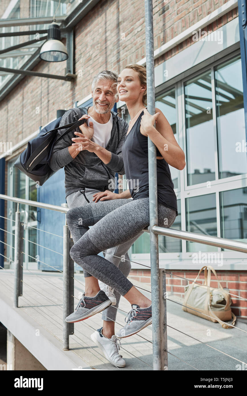 Ritratto di uomo maturo con borsa sportiva e la giovane donna di fronte palestra guardare qualcosa Foto Stock