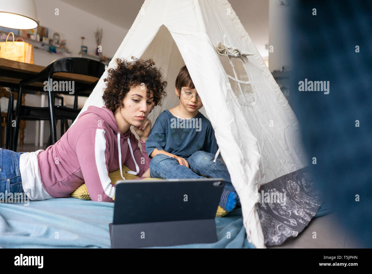 Madre e figlio giacente in gioco tenda, guardare film su tablet Foto Stock