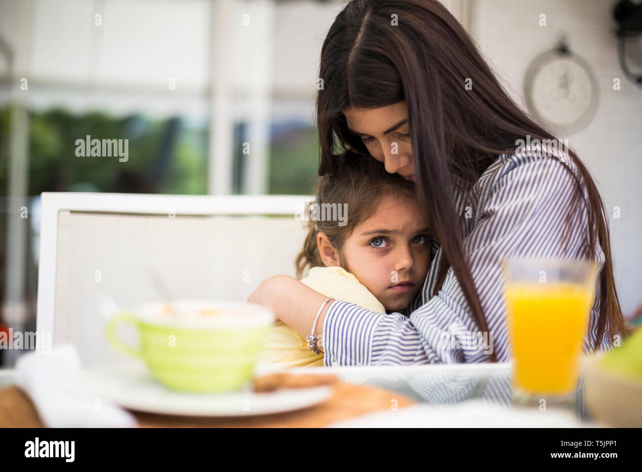La madre che abbraccia il suo triste figlia durante la colazione a casa Foto Stock