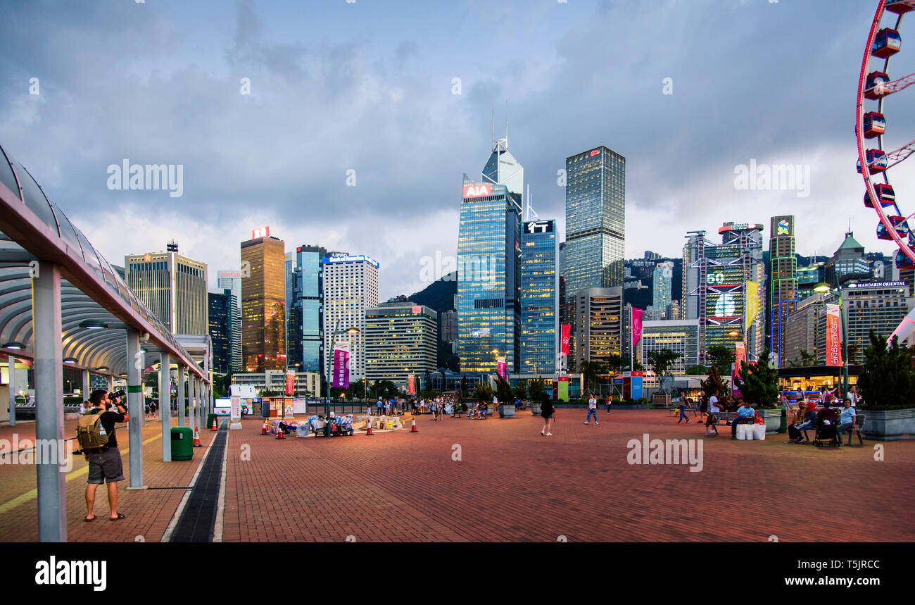 Hong Kong - Agosto 8, 2018: uomo di scattare una foto di grattacieli ed edifici moderni dell'isola di Hong Kong distretto centrale al tramonto Foto Stock