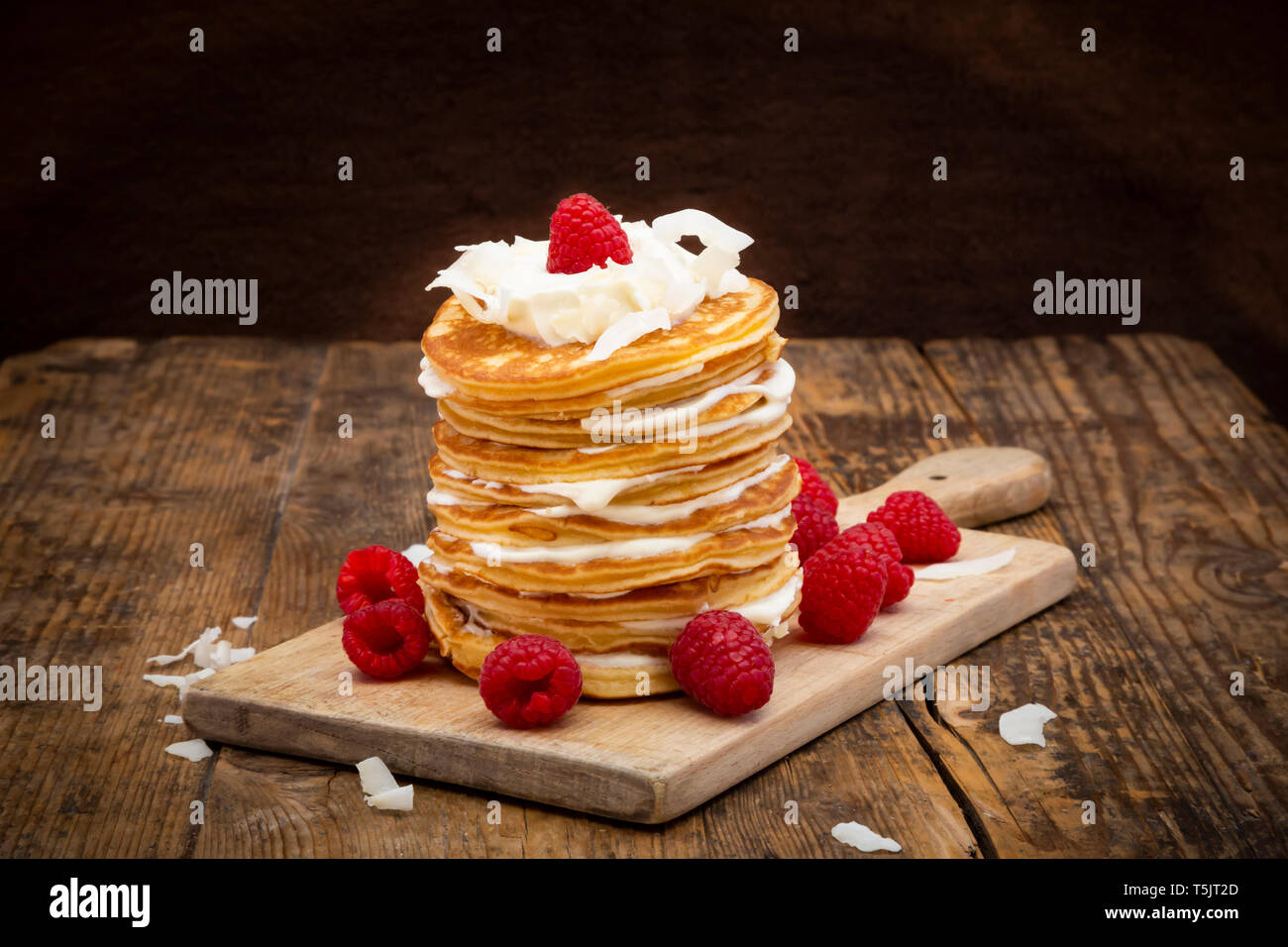Frittelle di farina di mandorle con lamponi, yogurt greco e scaglie di noce di cocco sul pannello di legno Foto Stock