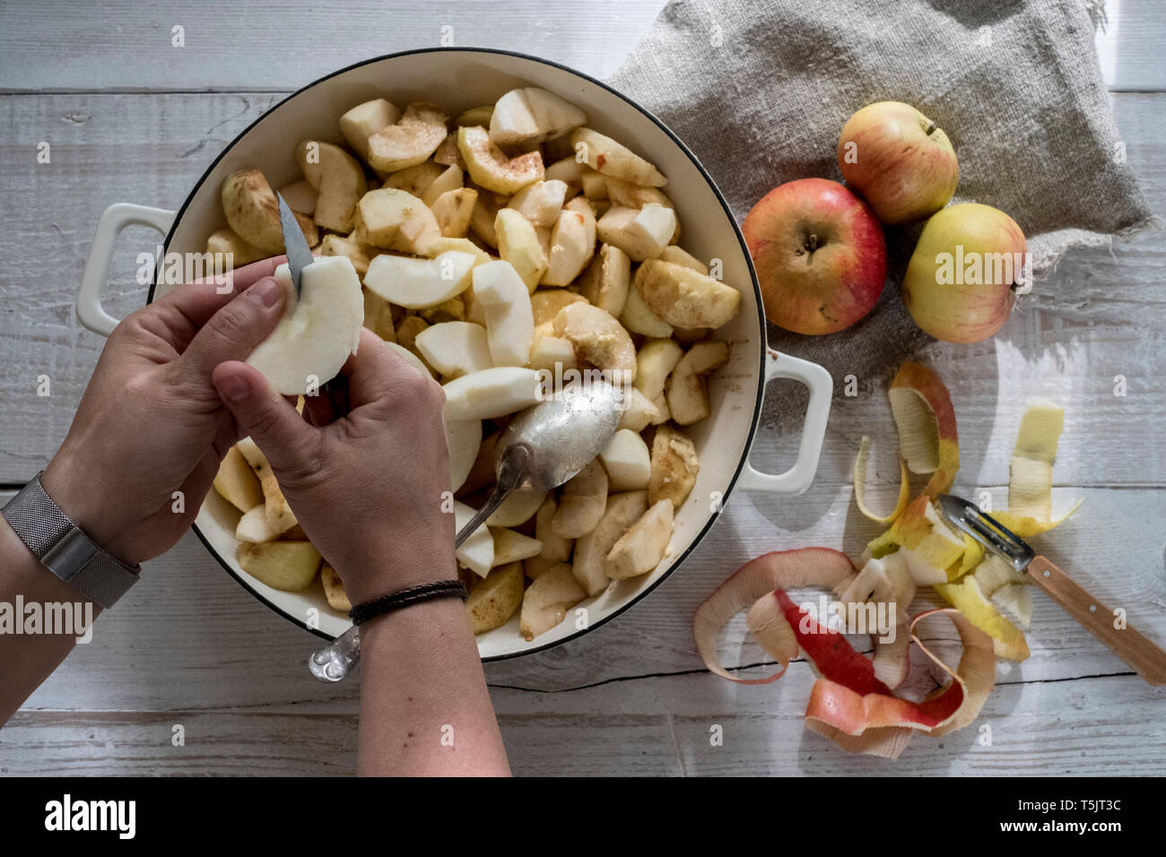 Angolo alto close up della persona che immetta le mele in un round in una teglia da forno. Foto Stock