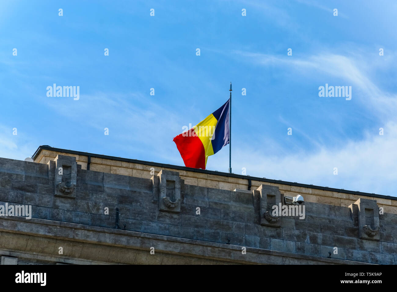 Bandiera rumena su un tetto contro il cielo blu Foto Stock
