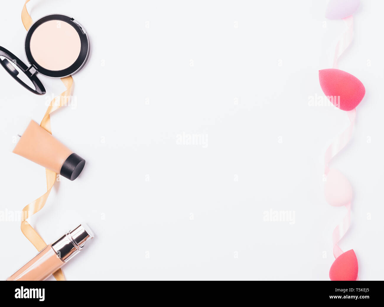 Piatto telaio laici donne cosmetici correttivi per affrontare anche la tonalità della pelle e il trucco spugne per la sua applicazione, vista dall'alto su sfondo bianco. Foto Stock