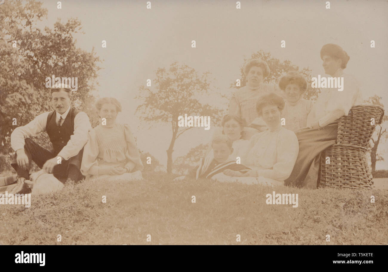 Vintage Cartolina fotografica che mostra un Edwardian famiglia socializzazione all'esterno. Foto Stock