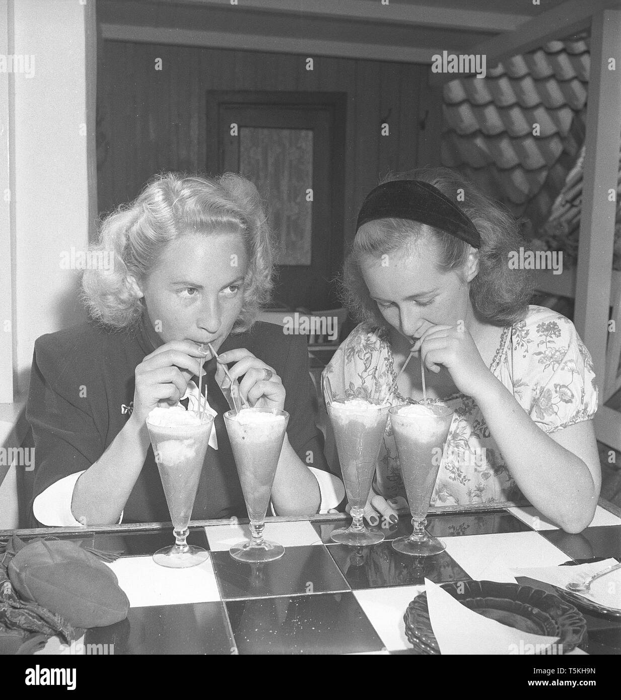 1940s'attrice. Un bicchiere di dessert drink non è sufficiente. Questi due giovani donne hanno due bicchieri ciascuno e bevande da loro con cannucce. Foto Kristoffersson ref U115-1. La Svezia 1946 Foto Stock