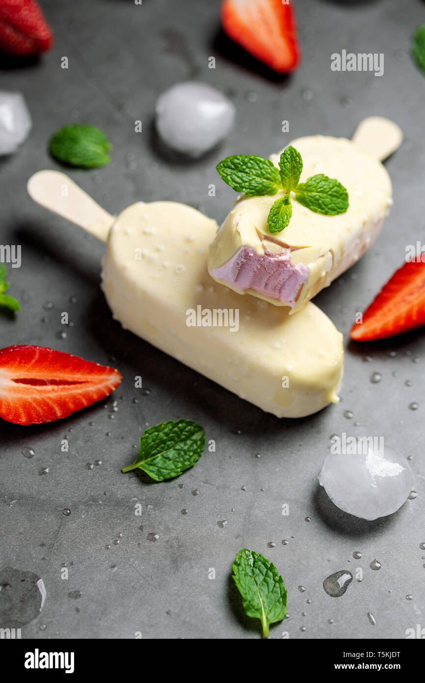 Gelato alla fragola stick ricoperto di cioccolato bianco Foto Stock