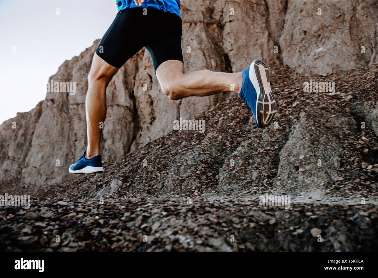 Gambe uomo runner in esecuzione sulla montagna sentiero di pietre Foto Stock