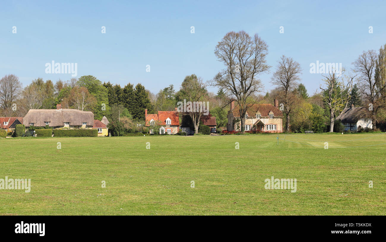 Una fila di inglesi tradizionali case di villaggio in Oxfordshire con village green e campo da cricket in primo piano Foto Stock