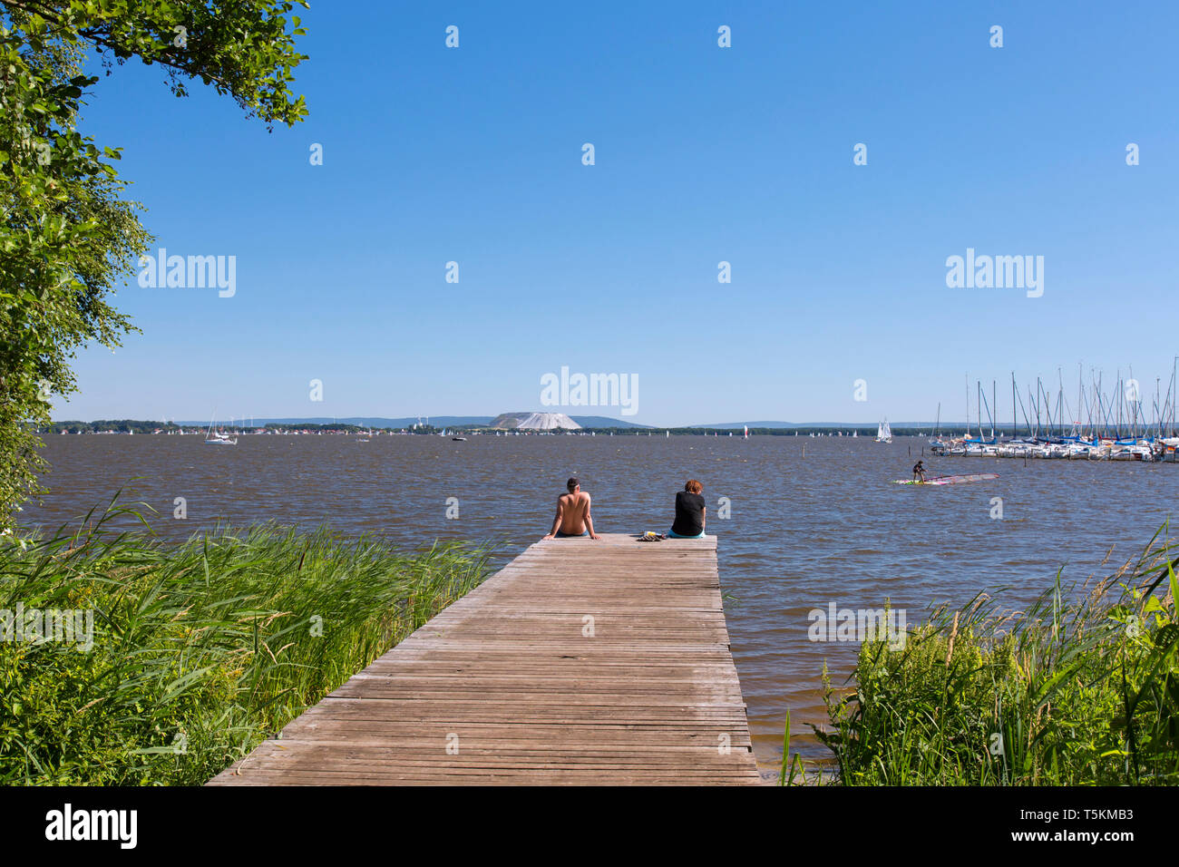 Giovane seduto sul molo al Lago Steinhude / Steinhuder Meer in estate, Mardorf, Bassa Sassonia / Bassa Sassonia, Germania Foto Stock
