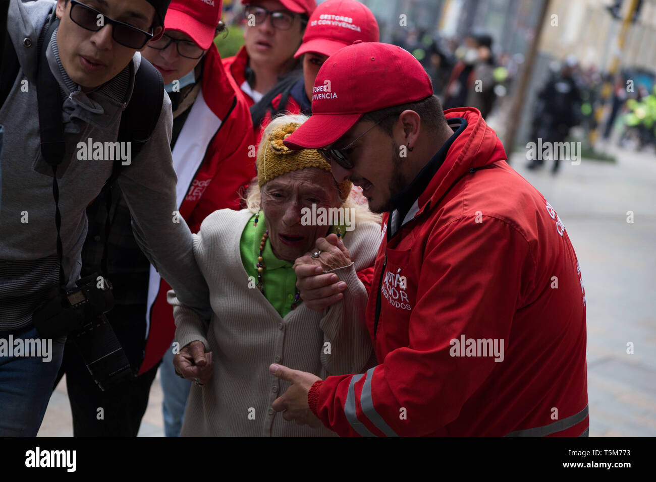 Bogotà, Colombia. Xxv Aprile, 2019. I giovani stanno contribuendo a una donna anziana dopo ha ottenuto in discussioni tra studenti e membri della ESMAD polizia durante una manifestazione contro il Presidente Duque del governo il piano di sviluppo nazionale. Credito: Yulieth Rincon/dpa/Alamy Live News Foto Stock