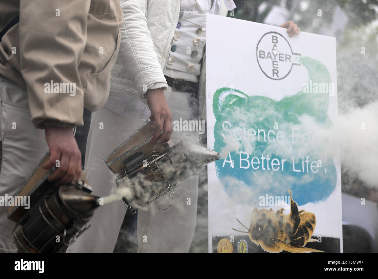 Bonn, Germania. 26 apr, 2019. Gli apicoltori utilizzano un fumatore a generare fumo, mentre i partecipanti arrivano a Bayer annuali di assemblea degli azionisti. Numerose associazioni e iniziative hanno protestato contro la politica della società dell'agrochimica e aziende farmaceutiche. Credito: Oliver Berg/dpa/Alamy Live News Foto Stock