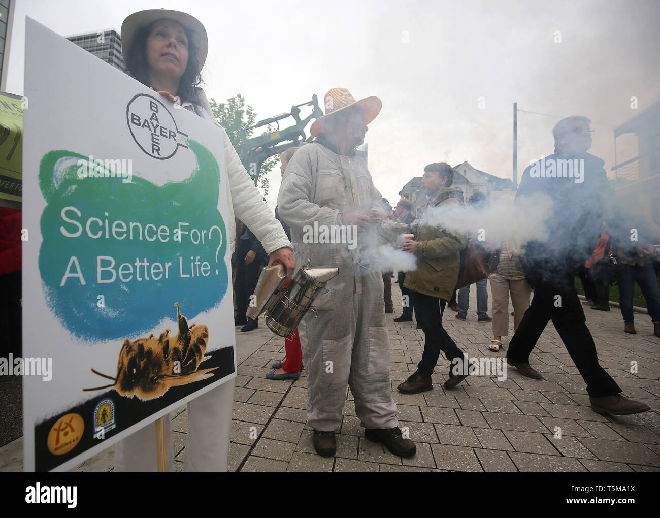 Bonn, Germania. 26 apr, 2019. Gli apicoltori utilizzano un fumatore a generare fumo, mentre i partecipanti arrivano a Bayer annuali di assemblea degli azionisti. Numerose associazioni e iniziative hanno protestato contro la politica della società dell'agrochimica e aziende farmaceutiche. Credito: Oliver Berg/dpa/Alamy Live News Foto Stock