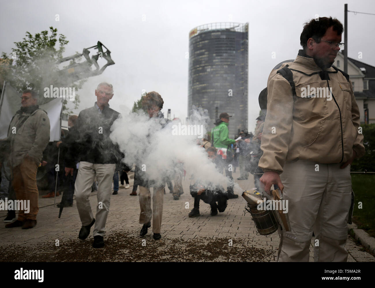 Bonn, Germania. 26 apr, 2019. Gli apicoltori utilizzano un fumatore a generare fumo, mentre i partecipanti arrivano a Bayer annuali di assemblea degli azionisti. Numerose associazioni e iniziative hanno protestato contro la politica della società dell'agrochimica e aziende farmaceutiche. Credito: Oliver Berg/dpa/Alamy Live News Foto Stock