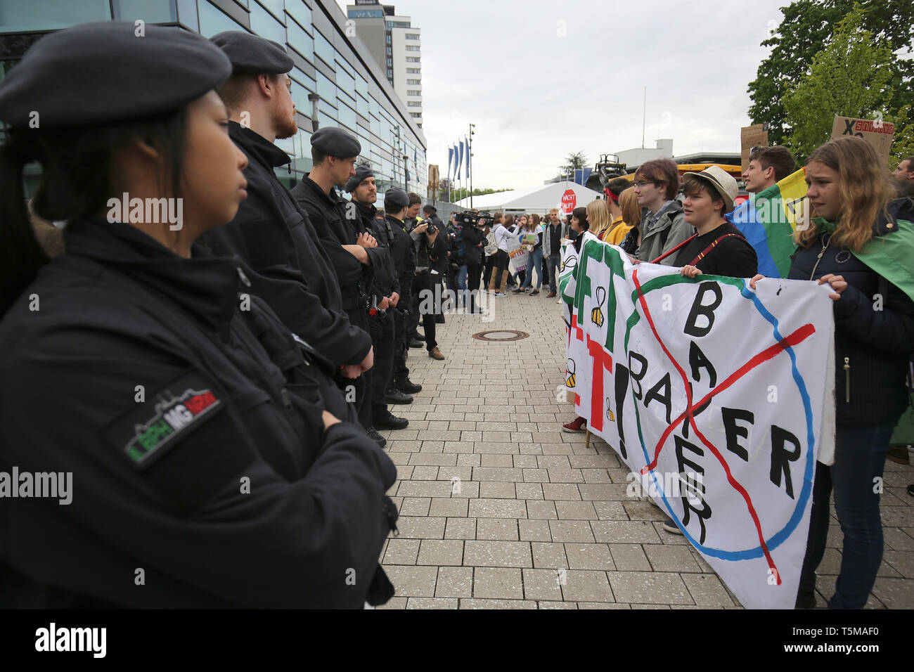 Bonn, Germania. 26 apr, 2019. Poliziotti di stare in piedi in fila nella parte anteriore del clima attivisti del "Venerdì per il futuro " movimento che stanno dimostrando di fronte Bayer annuali di assemblea degli azionisti. Numerose associazioni e iniziative hanno protestato contro la politica della società dell'agrochimica e aziende farmaceutiche. Credito: Oliver Berg/dpa/Alamy Live News Foto Stock