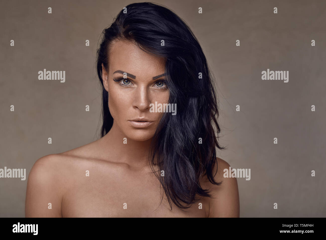 Bella donna di mezza età con le spalle nude e i suoi lunghi capelli scuri  aleggiava sopra una spalla cercando seriamente la fotocamera in una testa e  spalle Foto stock - Alamy