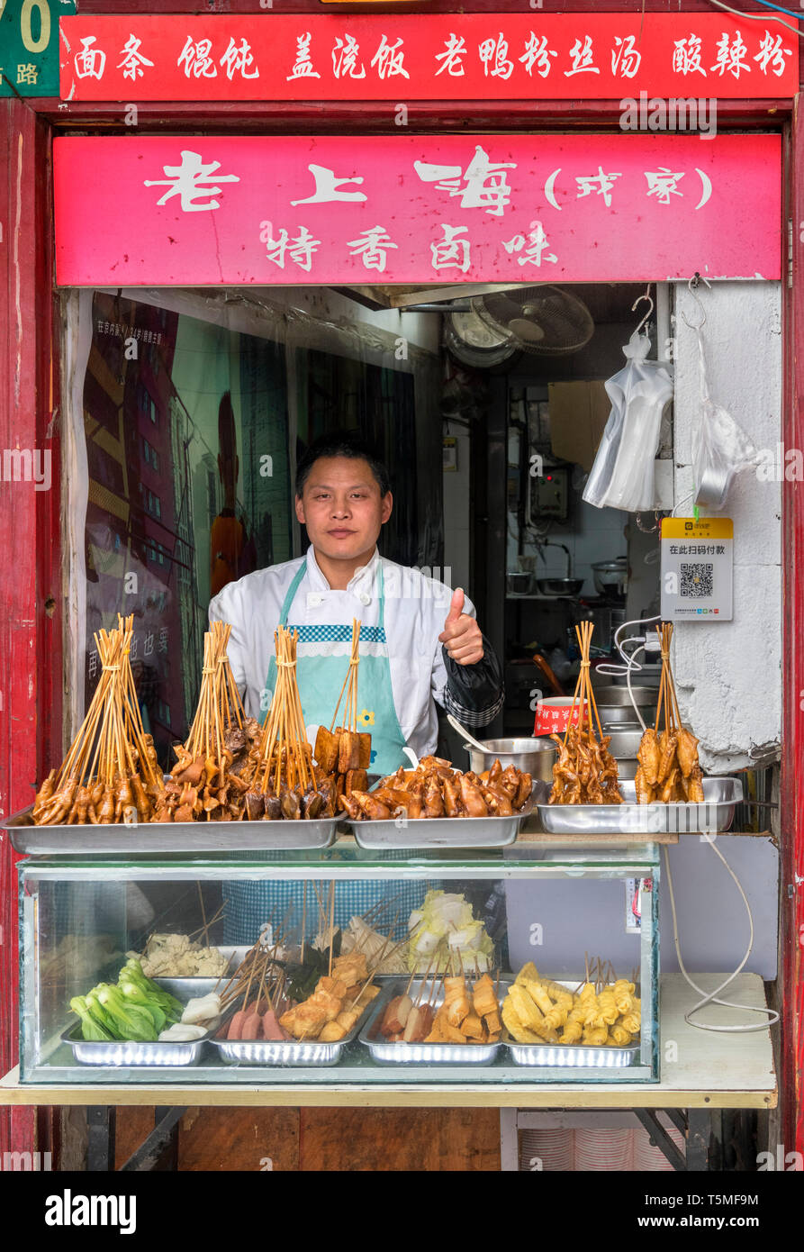 Fornitore dando un pollice fino a un cibo tradizionale stallo nella Città Vecchia, Shanghai, Cina Foto Stock