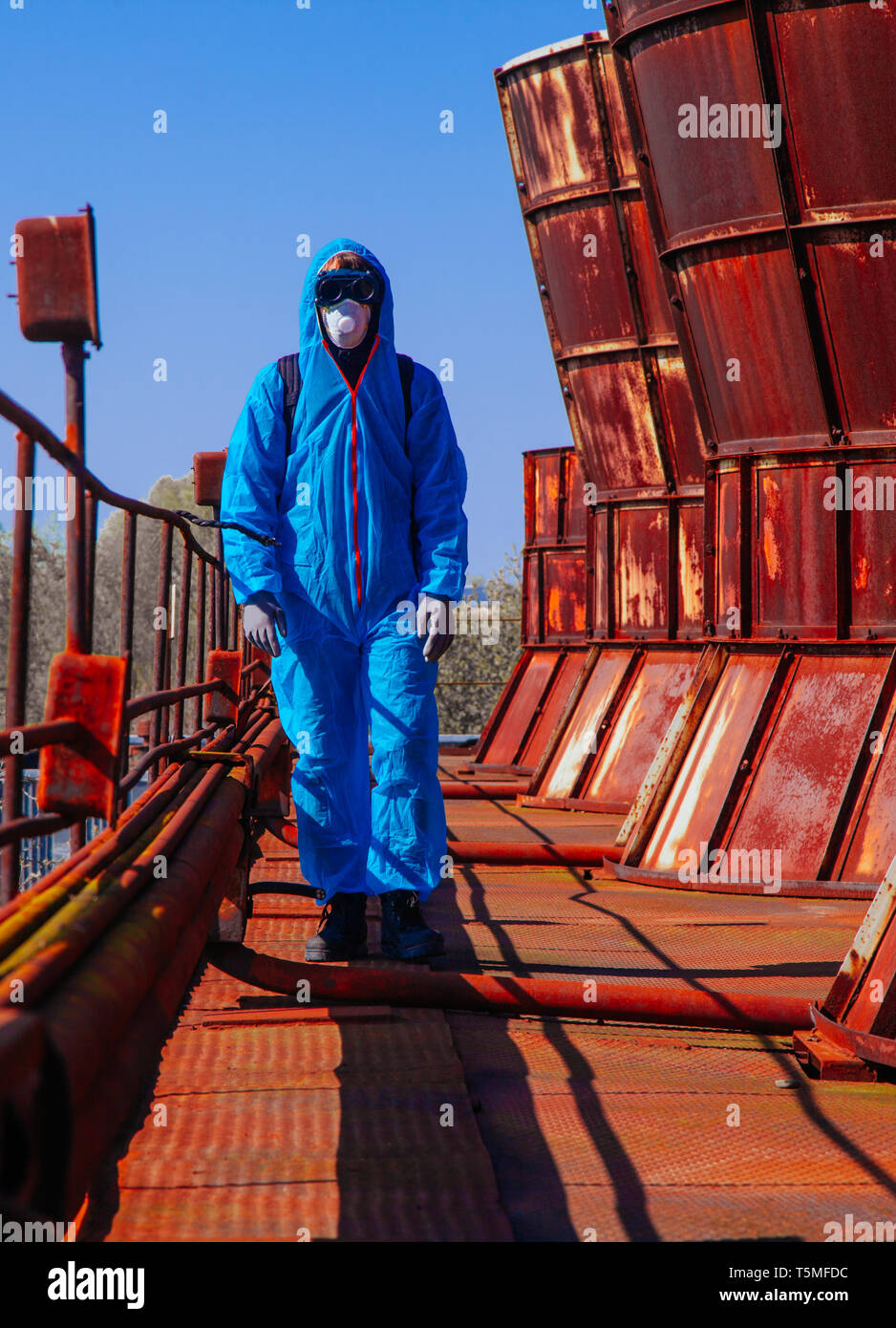 Gli uomini in blu tuta protettiva presso la vecchia fabbrica distrutta. Concetto di inquinamento ambientale e la catastrofe ecologica. Foto Stock