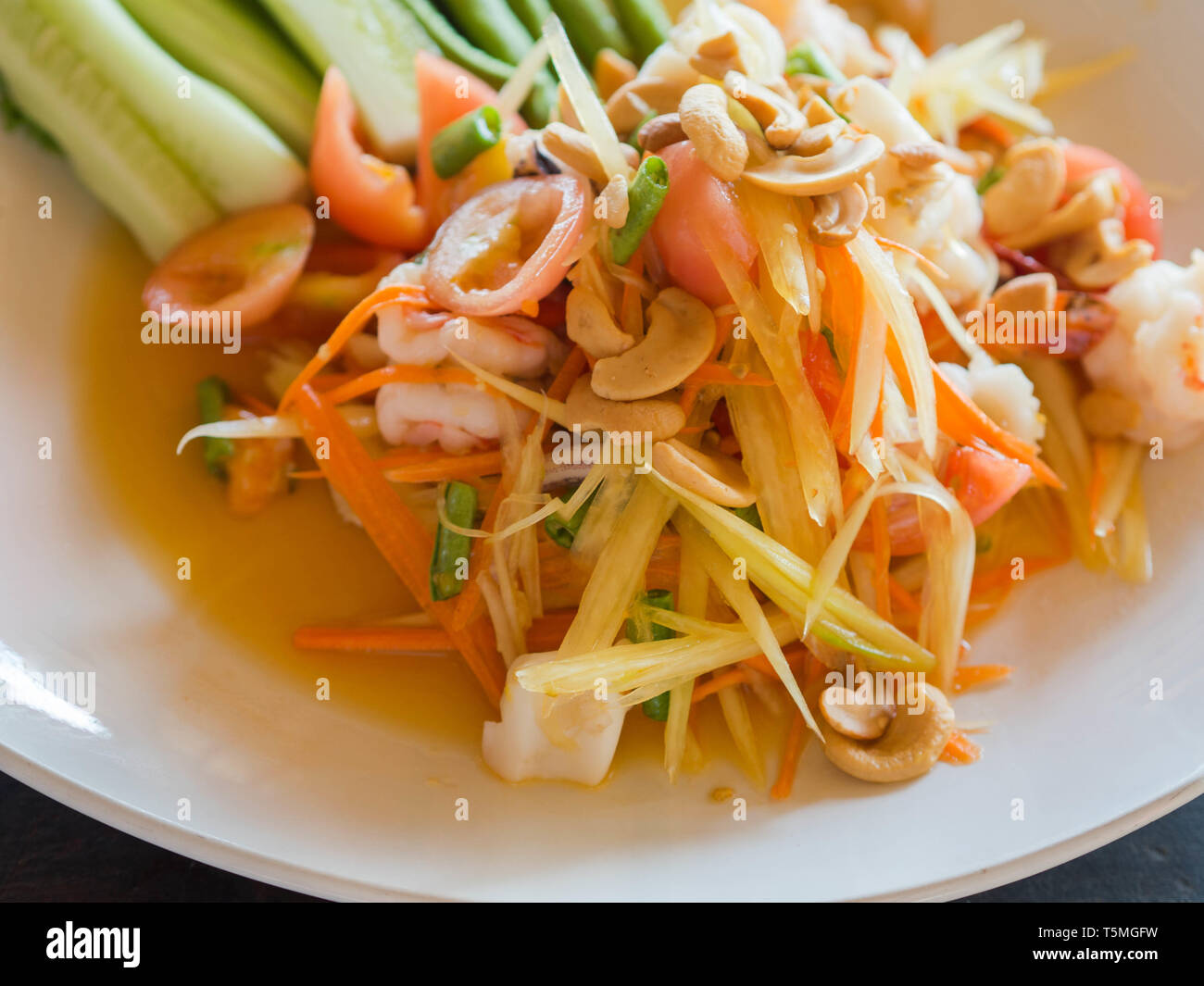 Le autentiche con insalata di papaya verde, verdure fresche e le erbe e i frutti di mare sulla piastra bianca nel ristorante tailandese Foto Stock