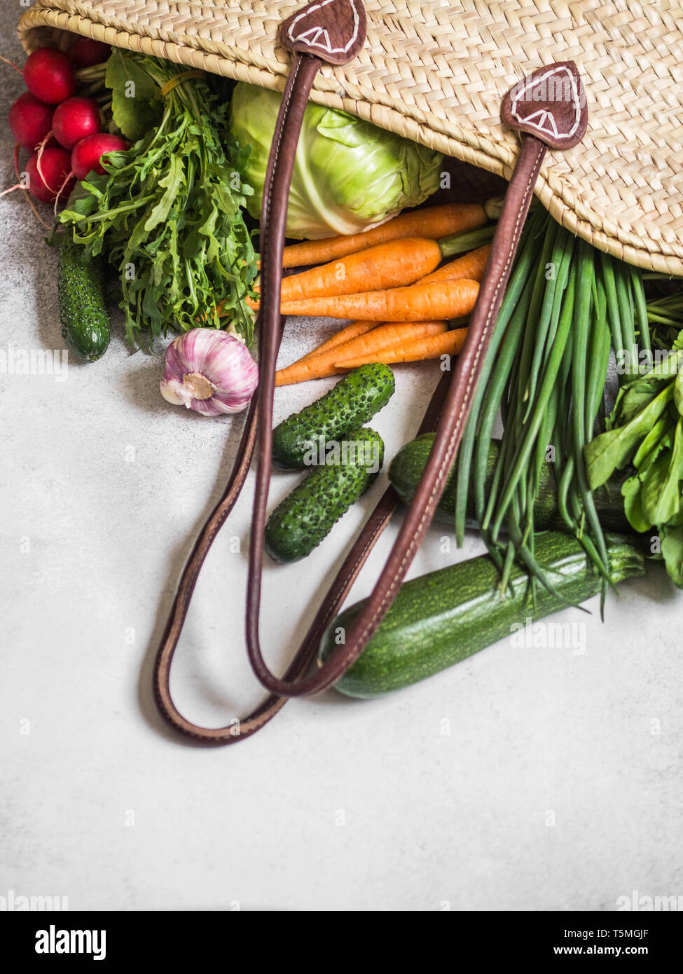 Paglia di vimini sacchetto pieno di naturali freschi ortaggi di primavera. Un sano vegetariano vegano cibo dal mercato locale dalle aziende agricole Foto Stock