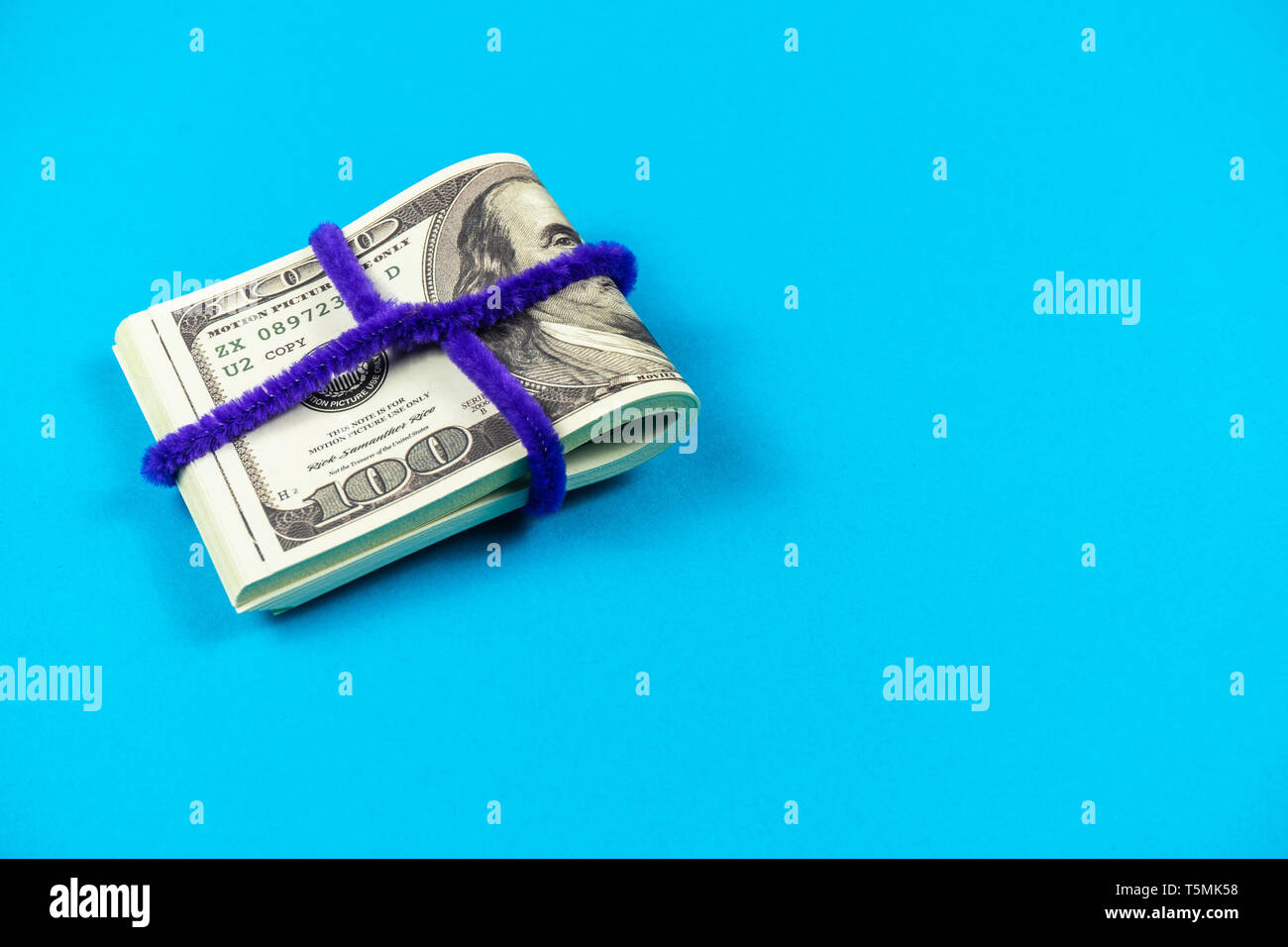 Le fatture del dollaro piegato a metà su fondo azzurro Foto Stock