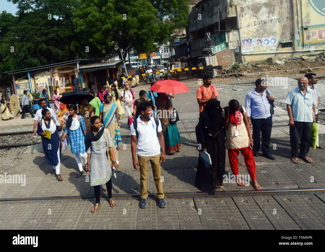 Pedoni che attraversano la linea ferroviaria a Chennai, India. Foto Stock