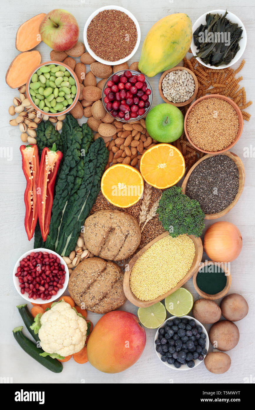 Super concetto alimentare per una dieta ad alto contenuto di fibre di frutta e ortaggi, grano intero panini, pasta integrale, noci, cereali, semi e spirulina in polvere. Foto Stock