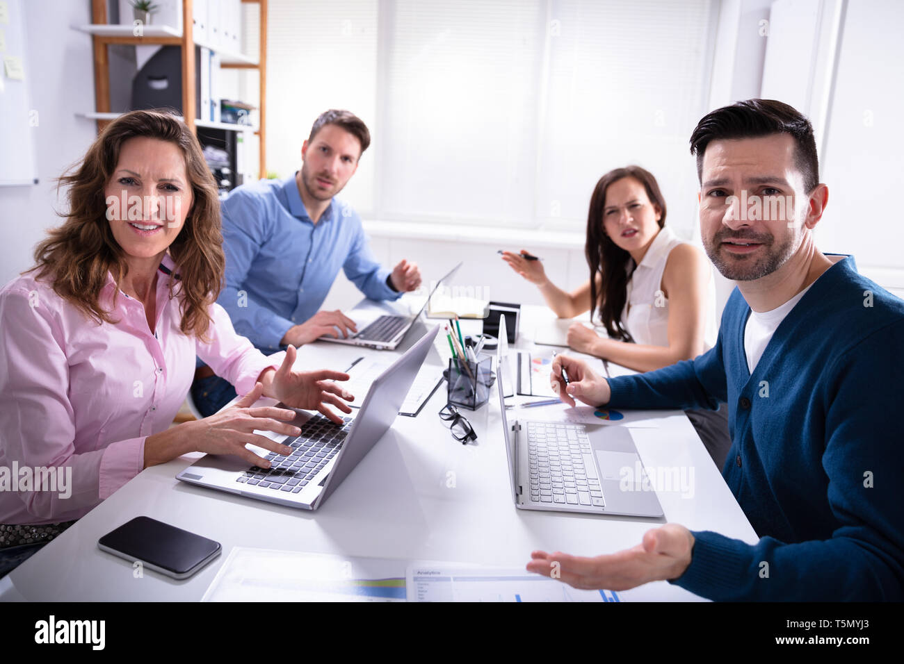 Un gruppo di dirigenti aziendali lamenta verso la telecamera in ufficio Foto Stock