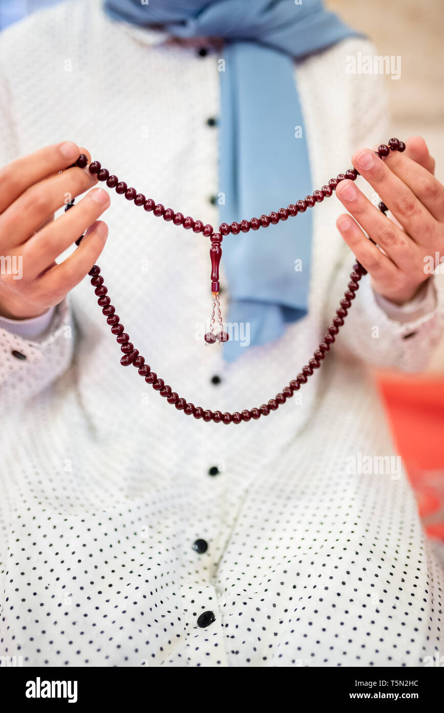 Vista ravvicinata di una donna musulmana mani in hijab tenendo Rosario con le sue mani e la preghiera.La religione pregando concetto. Foto Stock