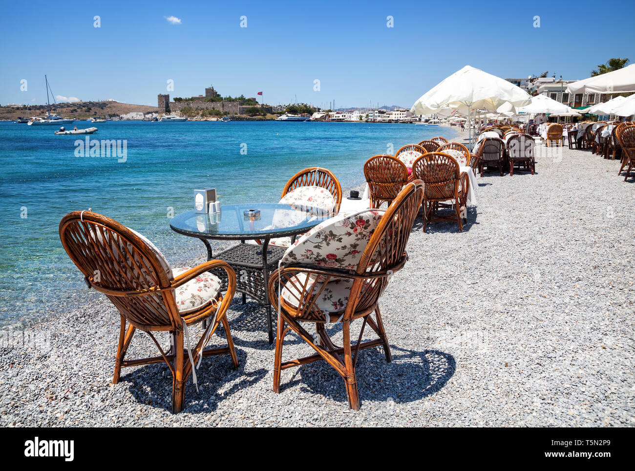 Carino tavolo e sedie e ombrellone in spiaggia al ristorante sul mare a bodrum, Turchia Foto Stock