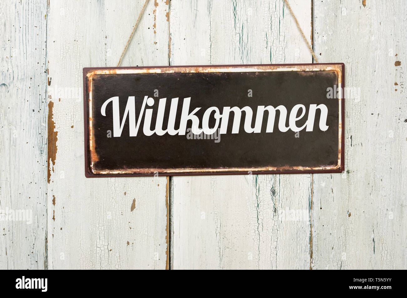 Il vecchio segno di metallo nella parte anteriore di un bianco parete in legno - parola tedesca per il Benvenuto - Willkommen Foto Stock