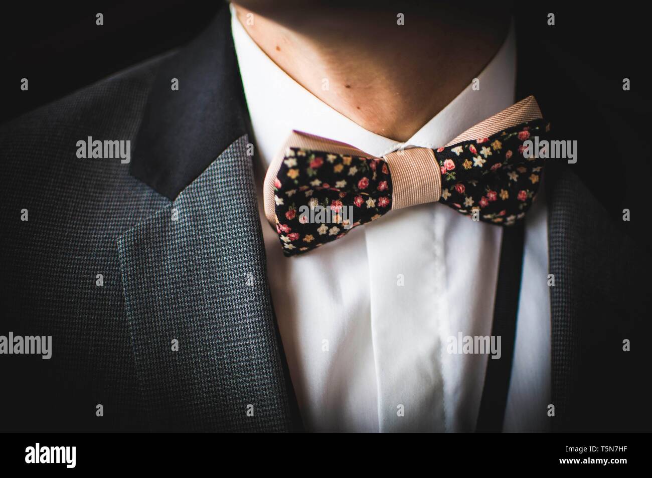 Bella brown bow tie con piccoli fiori colorati su una camicia bianca e  giacca grigia Foto stock - Alamy