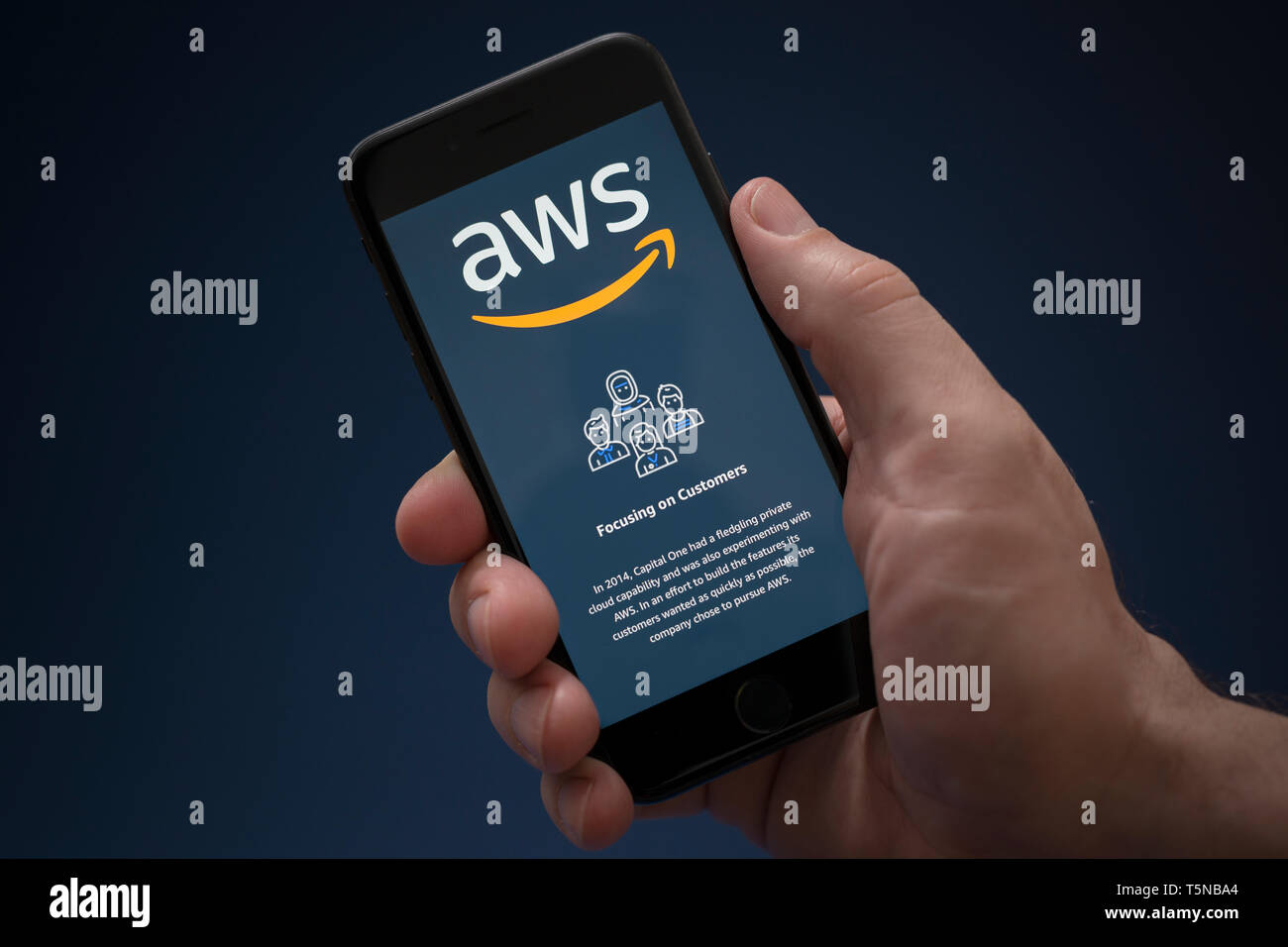 Un uomo guarda al suo iPhone che visualizza il Amazon Web Services (logo solo uso editoriale). Foto Stock