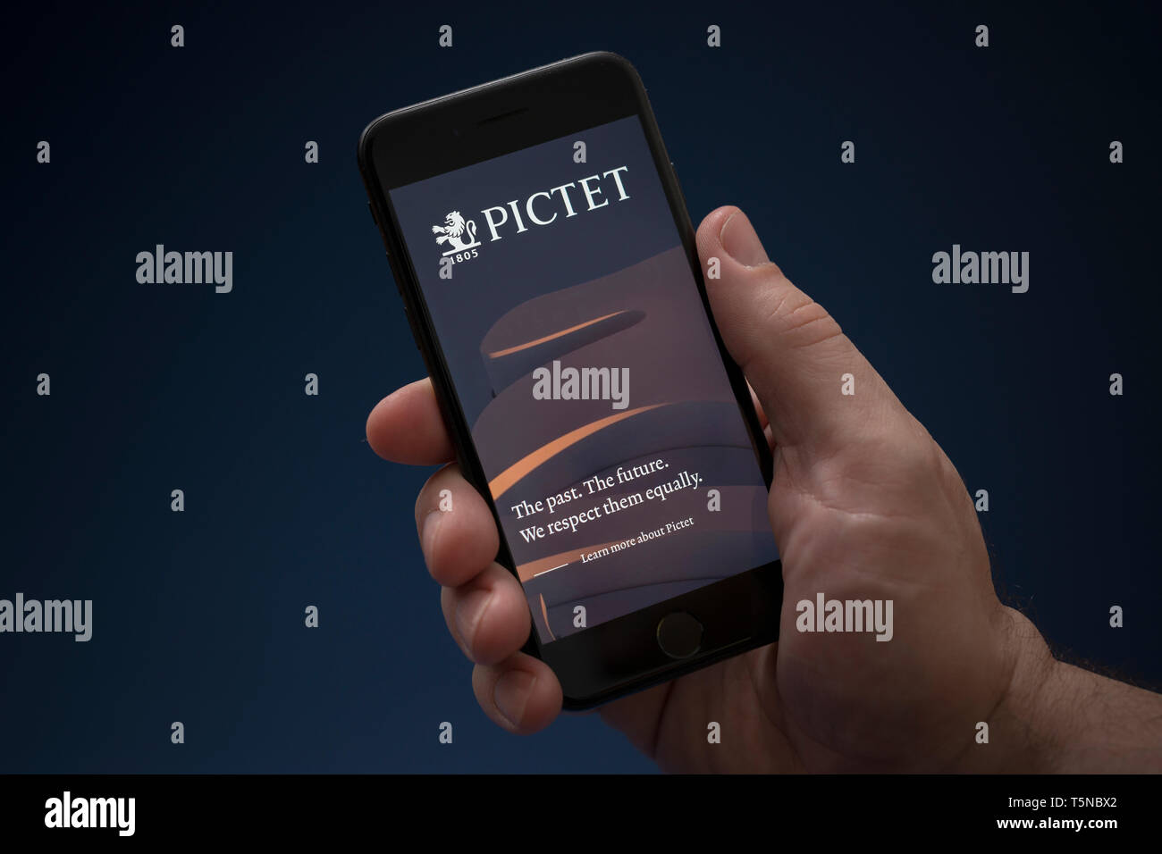 Un uomo guarda al suo iPhone che visualizza il logo di Pictet (solo uso editoriale). Foto Stock