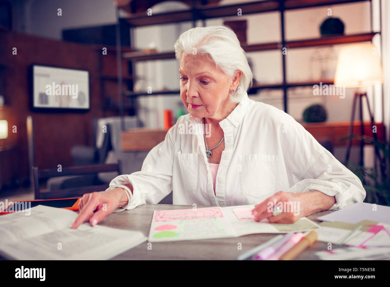 Donna che indossa camicia bianca leggendo il libro avente tempo libero Foto Stock