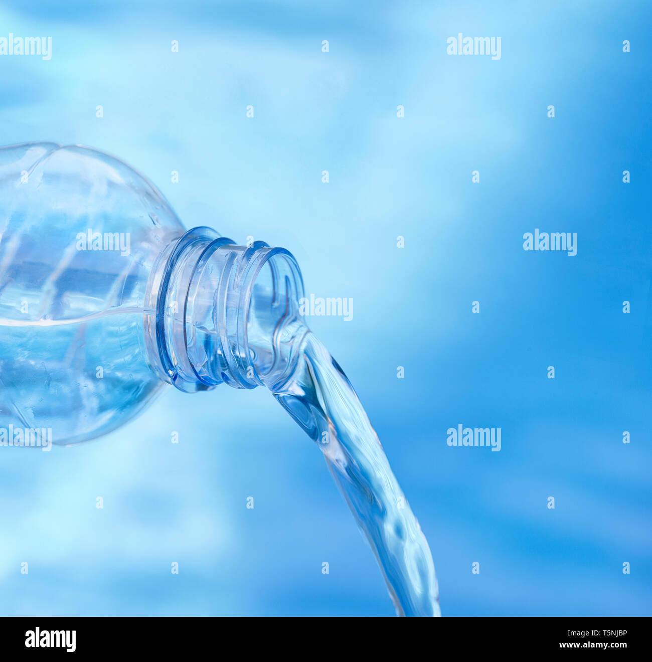 Profondità di campo. Soft focus di blu bottiglia versando acqua contro fresco e sfondo bluastro. Foto Stock