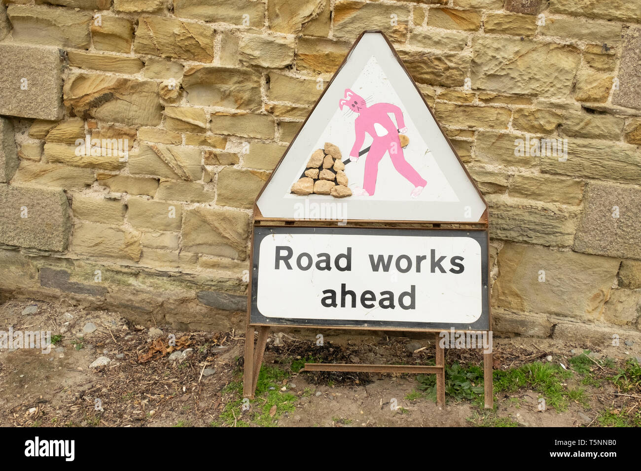 Alterato roadworks segno con coniglio rosa figura, in Cornovaglia, Inghilterra Foto Stock