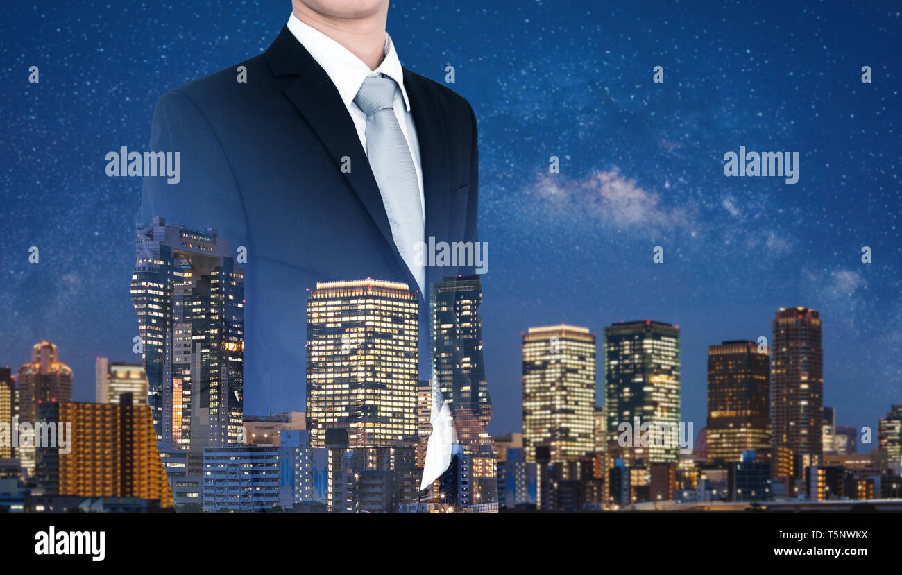 Il concetto di business, uomo d'affari in abito nero con doppia esposizione panoramica della città moderna di notte Foto Stock