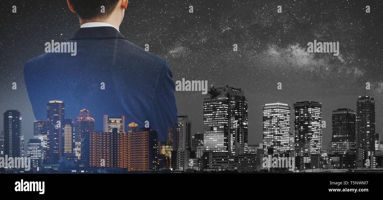 Il concetto di business, uomo d'affari in abito nero con doppia esposizione panoramica della città moderna di notte Foto Stock