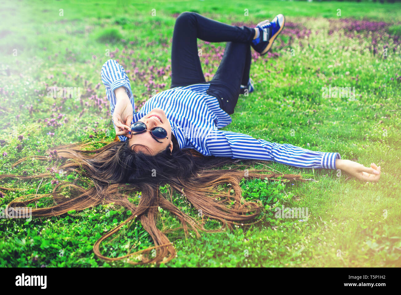 Giovane donna felice che si stesa su erba verde Foto Stock