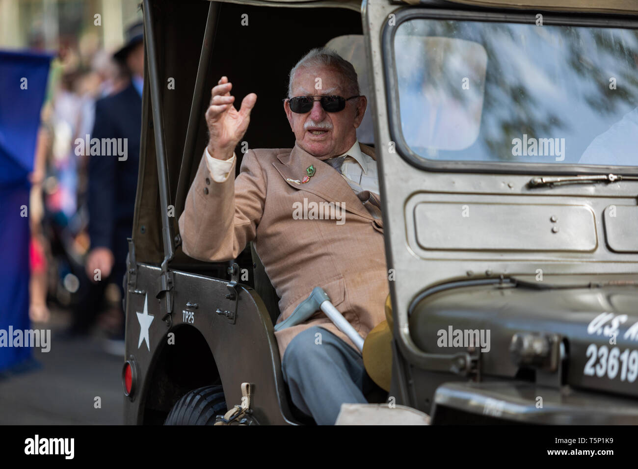 Un anziano veterano restituito nella sua escort veicolo gesticolando e dando pollice fino alla folla che acclamava e battendo le mani per lui, durante l'Anzac Day marzo Foto Stock
