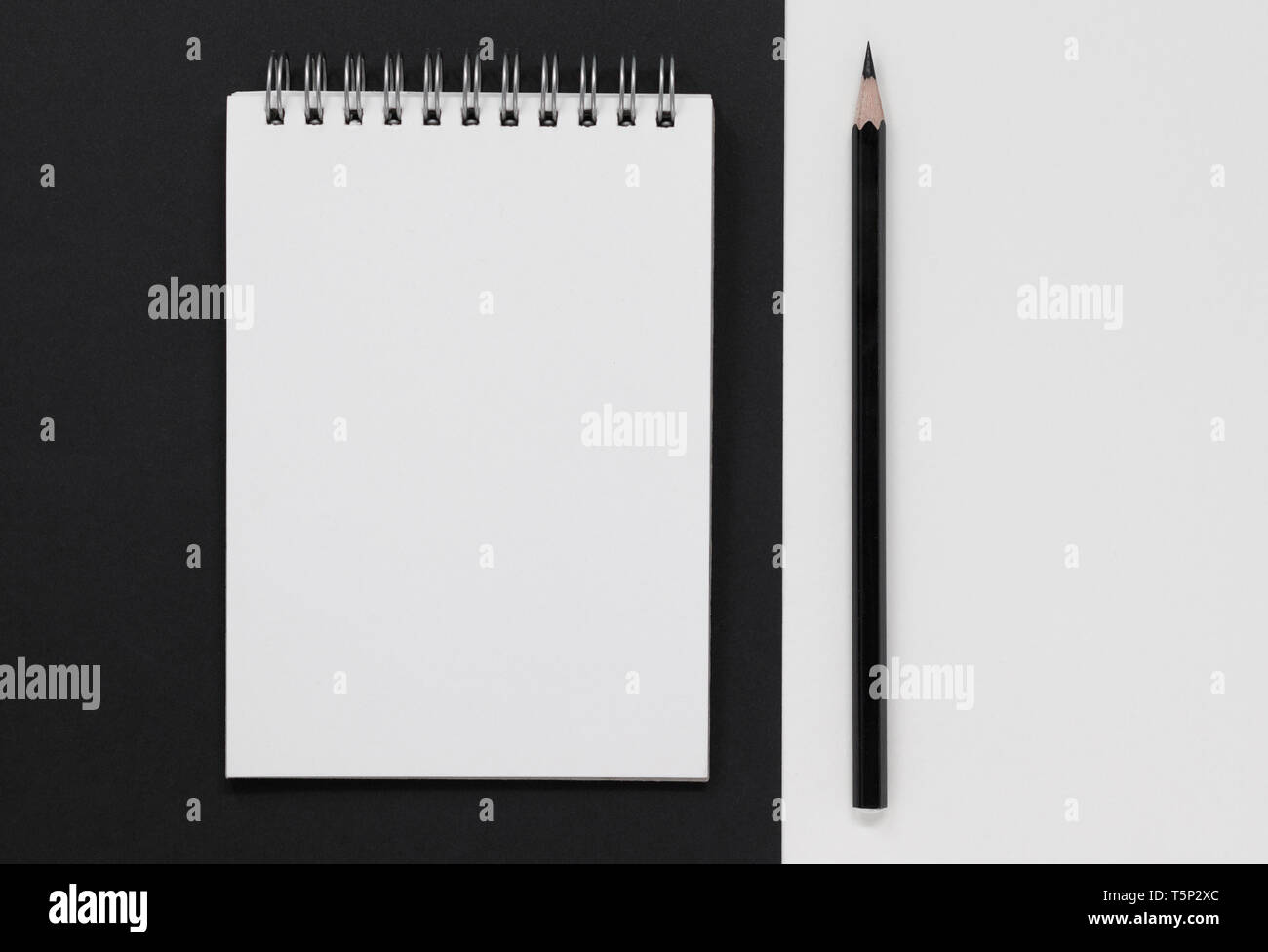 Schermata bianca vuota il blocco note e matita nera, su un nero e sfondo bianco. Lay piatto con copia spazio. Foto Stock