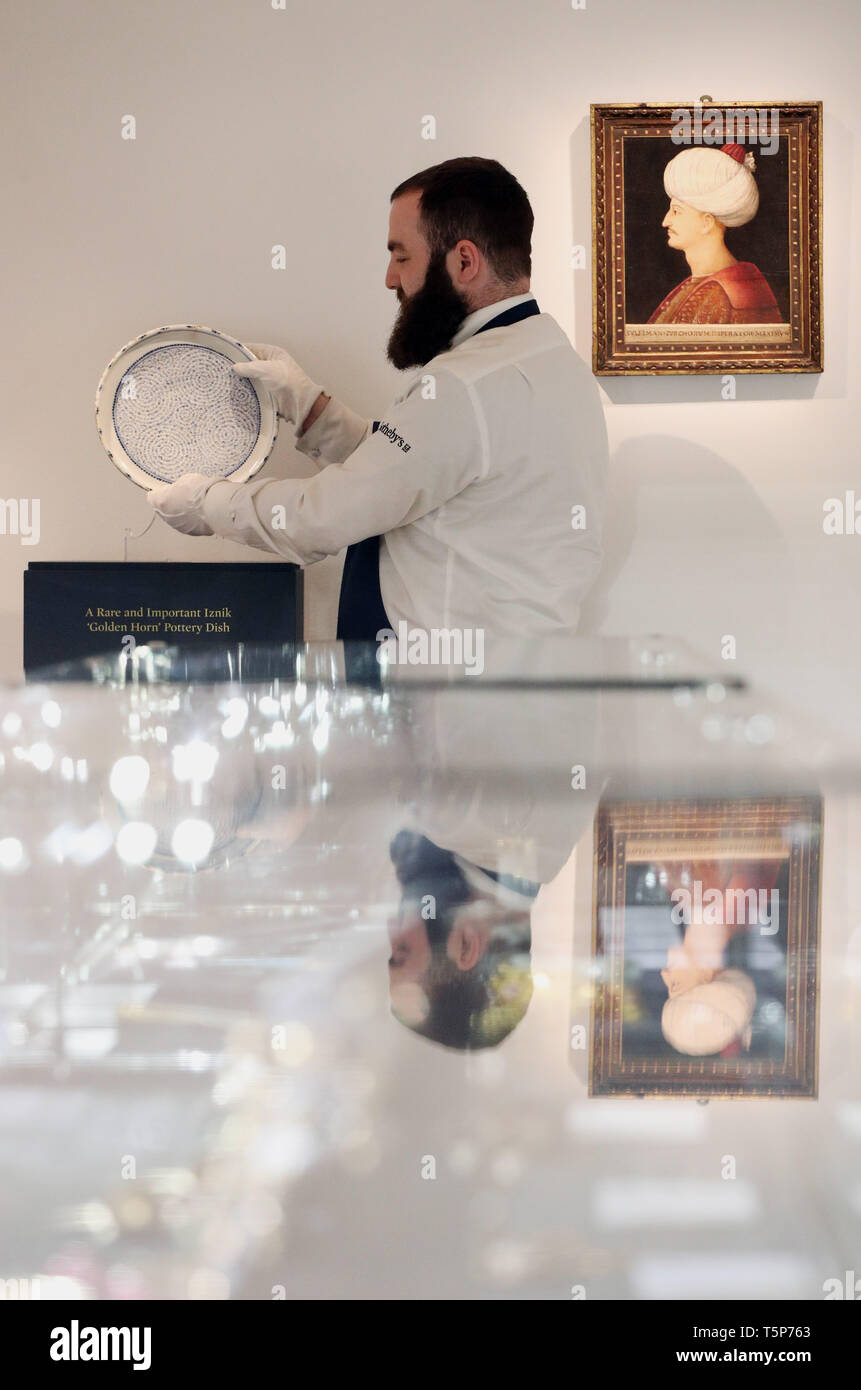 Una galleria tecnico pone una rara "Goldern Horn' ceramiche di Iznik piatto (sinistra) accanto a uncredited il ritratto veneziano di Suleyman il magnifico (destra) presso un'anteprima per la prossima Sotheby's Medio Orientale settimana d'arte vendita che si svolge il 30 aprile a Londra. Foto Stock