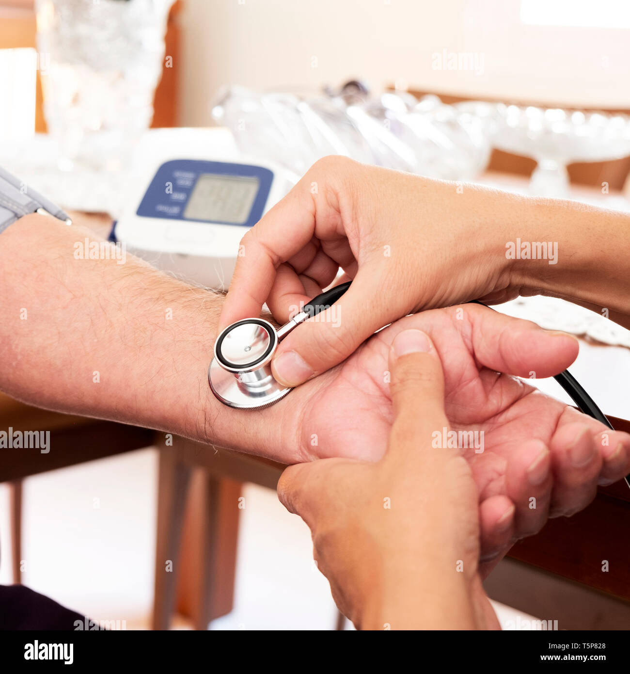 Primo piano di un medico caucasica uomo in camice bianco, la misurazione della pressione del sangue di un senior caucasica uomo paziente con uno sfigmomanometro a sua hom Foto Stock