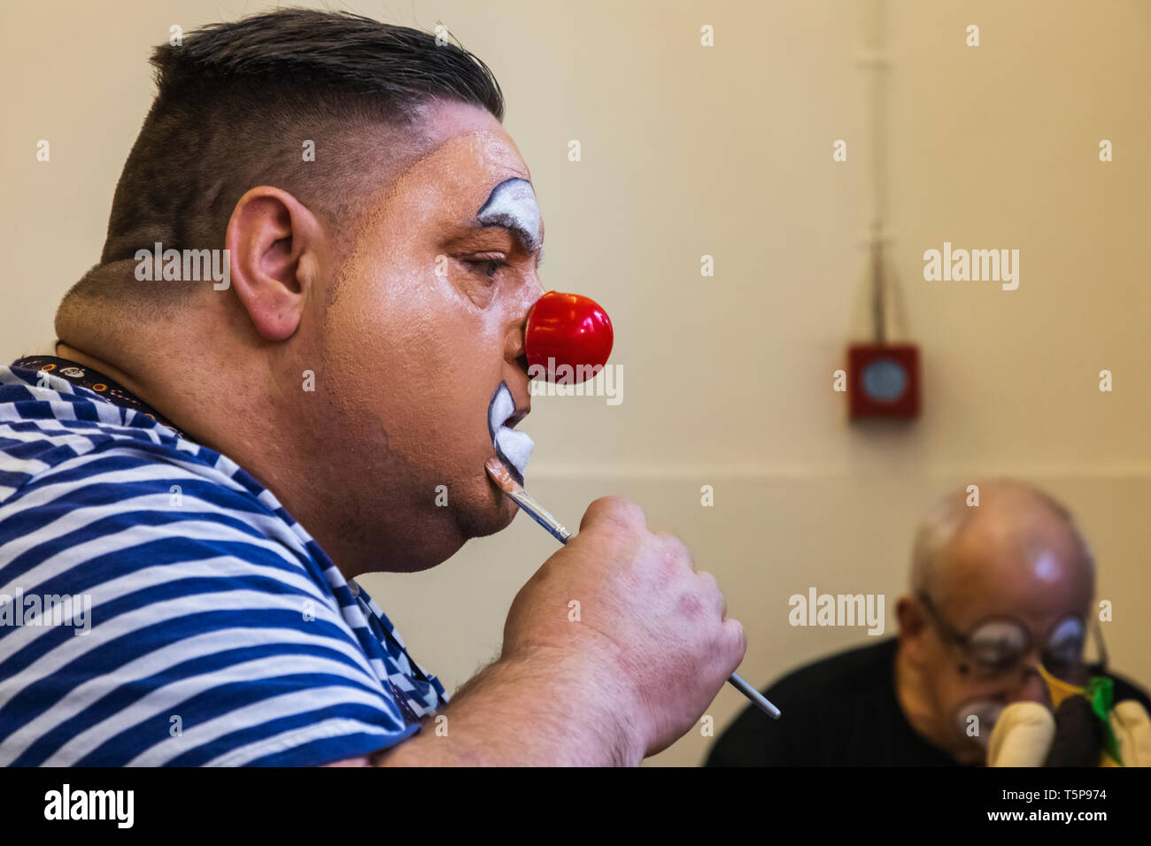 Inghilterra, Londra, l annuale Grimaldi clown servizio di chiesa in chiesa di Tutti i Santi, Haggerston, Clown con naso rosso di applicare il make-up Foto Stock