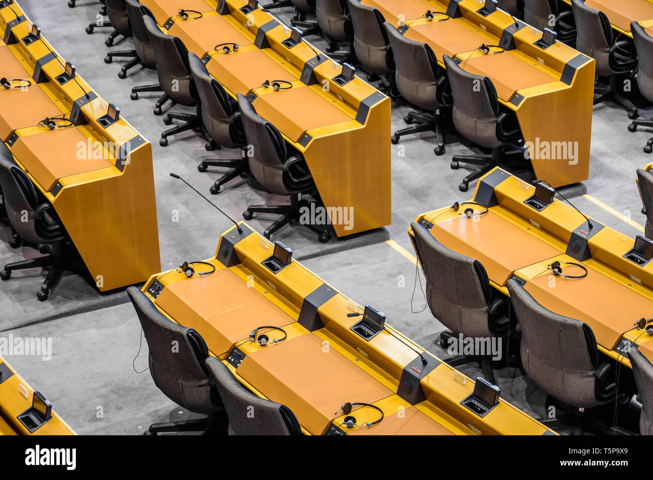 Vista ravvicinata di vuoto scrivanie con microfoni, cuffie e voto elettronico apparecchiature nell'emiciclo del Parlamento europeo a Bruxelles. Foto Stock