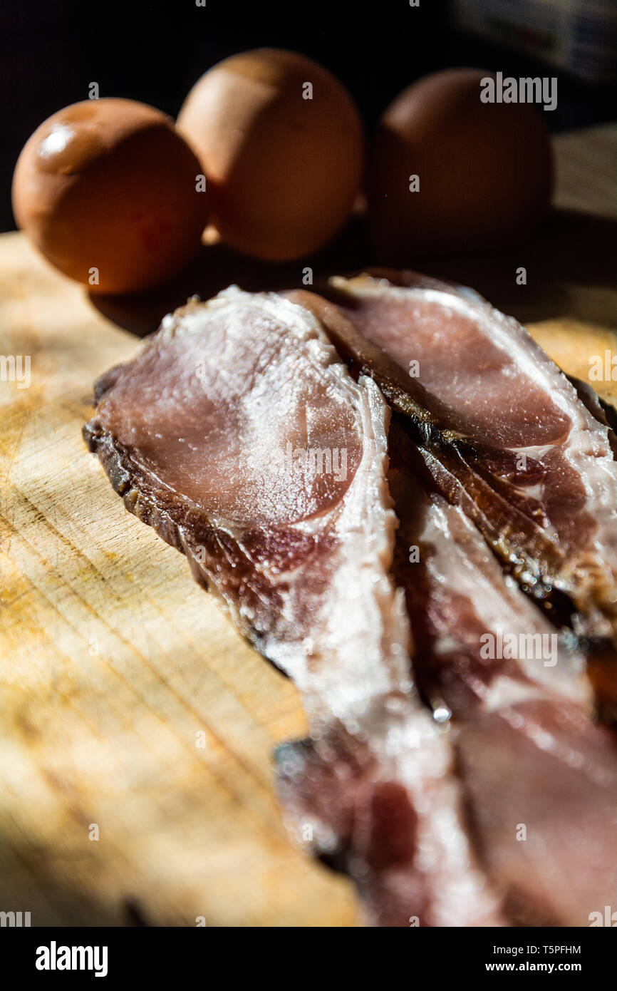 Due fette di materie, melassa torna con la gallina uova su un tagliere pronto per essere trasformato in una colazione cucinata. Foto Stock