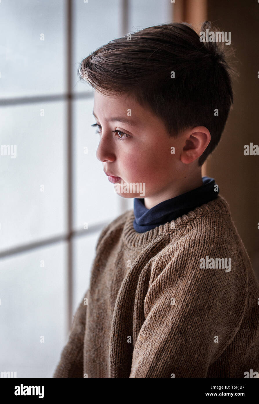 Razza mista Asian Caucasian boy indossando tan marrone in maglia di lana maglione di fronte giapponese shoji carta schermo Foto Stock