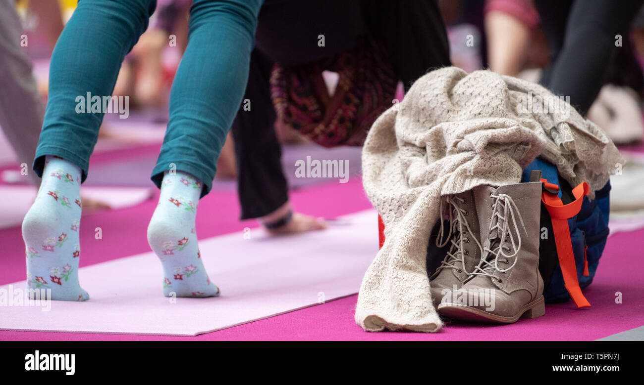 Stuttgart, Germania. 26 apr, 2019. Una donna sta facendo un esercizio alla massa di yoga. Ci sono le scarpe e una borsa accanto al tappetino e un maglione sulla parte superiore. Credito: Sebastian Gollnow/dpa/Alamy Live News Foto Stock